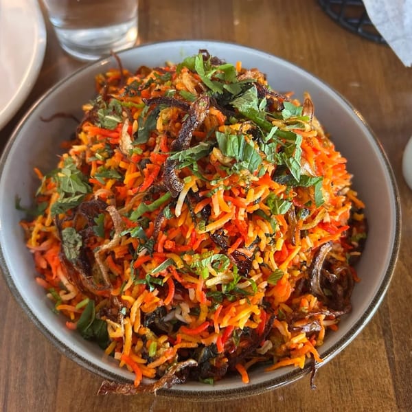 A vibrant Indian biryani dish from Gol Bowl, topped with fresh herbs and crispy fried onions.