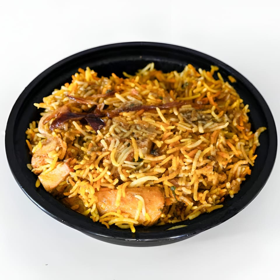 A black bowl filled with chicken biryani, featuring long-grain rice, chicken pieces, and caramelized onions.