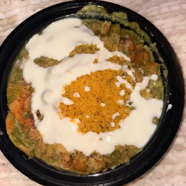 Gol Bowl's Indian dish with green curry, chickpeas, white sauce, and crispy orange topping.